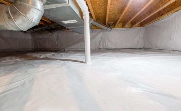 Crawl space fully encapsulated with thermoregulatory blankets and dimple board. Radon mitigation system pipes visible. Basement location for energy saving home improvement concept.